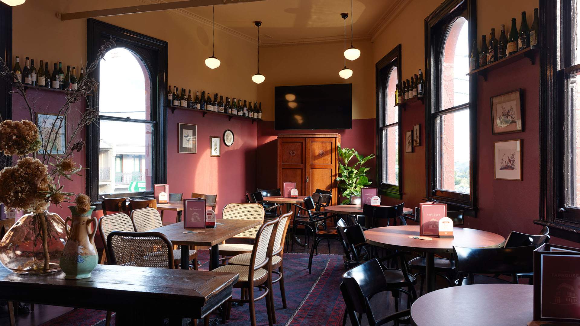 A classic pub interior featuring brown and yellow walls, a patterned blue and purple carpet, and wine bottles lining the shelves inside Darlinghurst's The Taphouse.