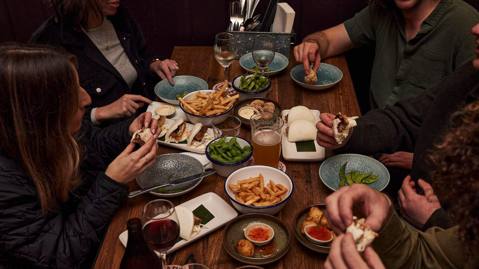 A group of people eating around a wooden table at The Hall at Welcome to Brunswick