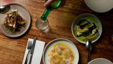 a drink being poured by small sharing plates on a table at Tipo 00