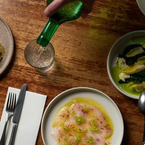 a drink being poured by small sharing plates on a table at Tipo 00