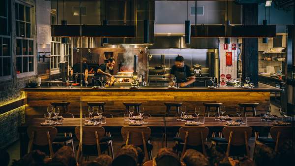 chefs cooking over the open pass with lots of fire and smoke - at Firedoor in Sydney