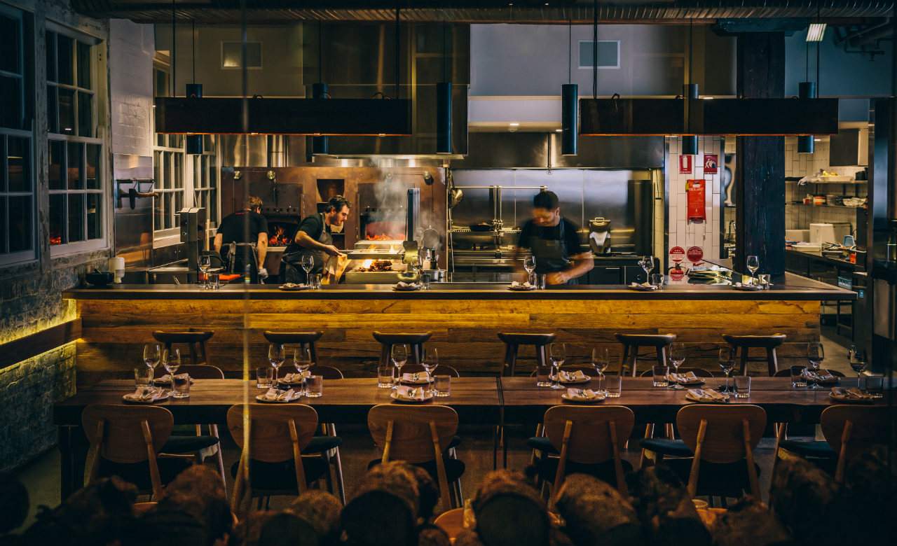 chefs cooking over the open pass with lots of fire and smoke - at Firedoor in Sydney