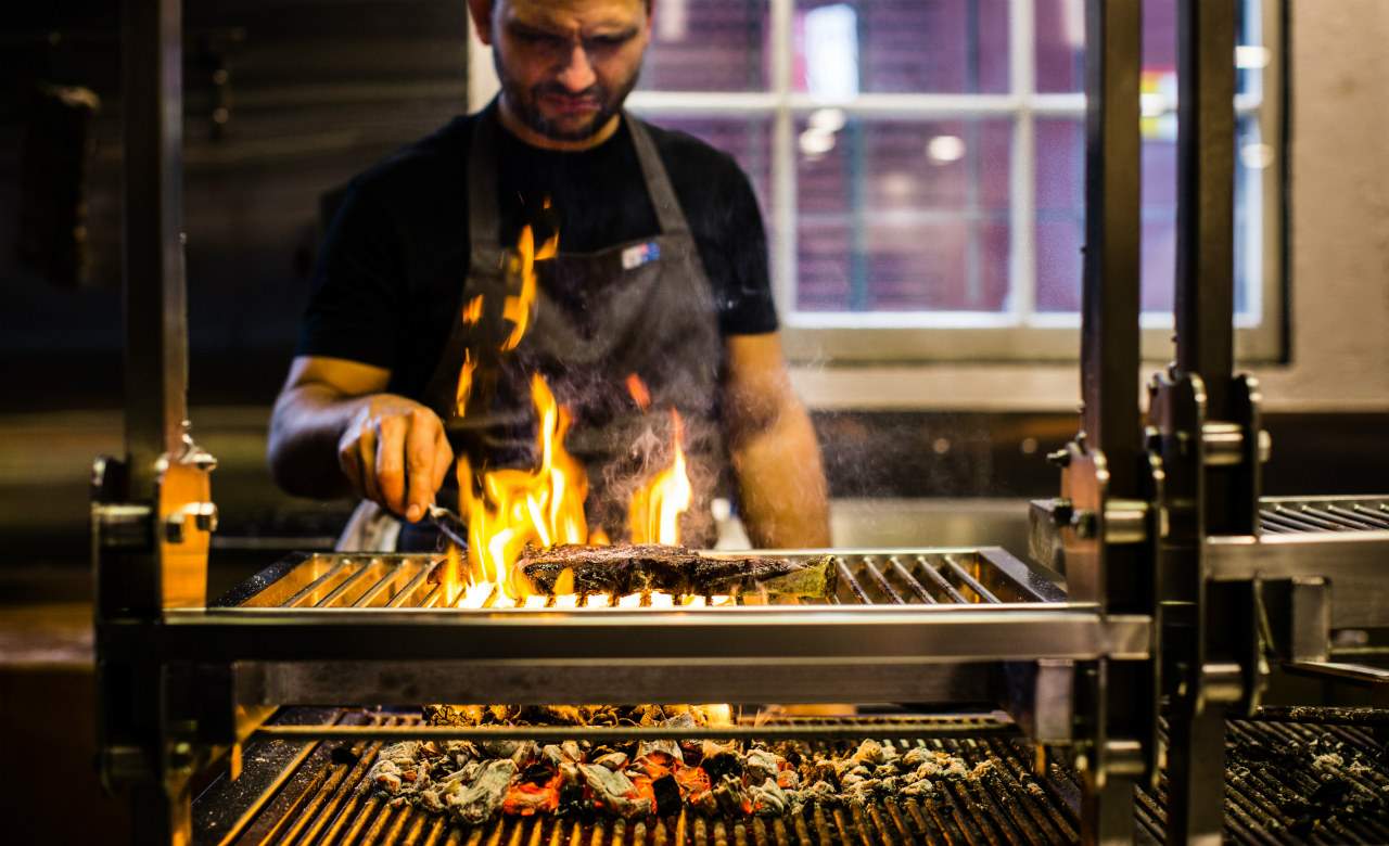 chef cooking a steak at Firedoor - over the coals - flames