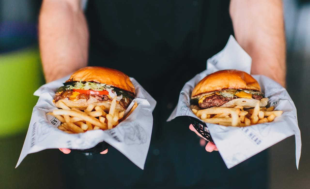 two burgers being held up by a chef from burger head - home to some of the best burgers in sydney