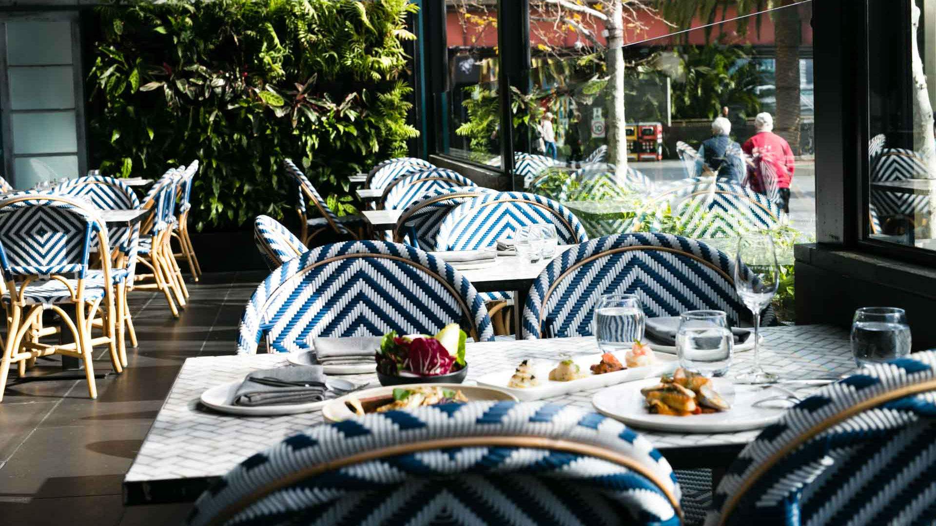 Food dishes placed on a set table in the outdoor dining space of The Atlantic Restaurant in Melbourne. 