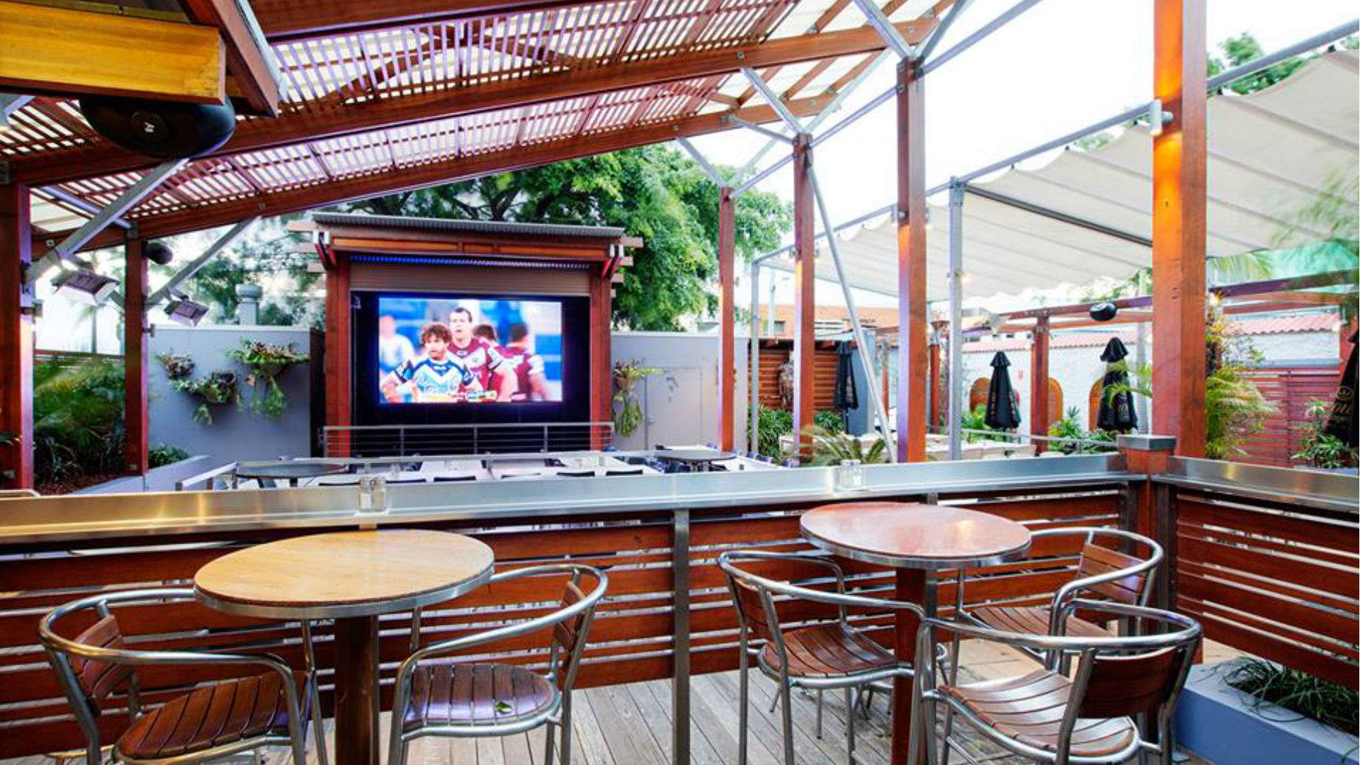 the covered beer garden with a large tv playing sport at The Breakfast Creek Hotel - one of the best sports bars in Brisbane