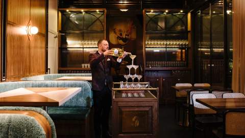 A man pouring Champagne on a tower of champagne glasses at Nick and Nora's - one of the best bars in Sydney - paramatta