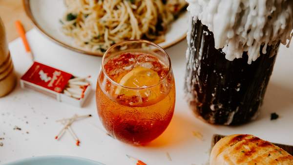 a negroni on a table with candles, matches and a bowl of pasta at Good Times in Fitzroy