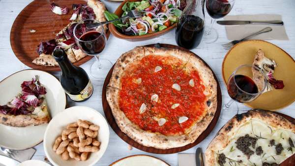table full of vegan pizzas, wine and salad — gigi's pizzeria - vegan restaurant in Sydney