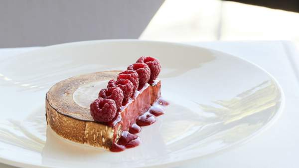 A close up shot of a meringue dessert topped with raspberries served on a white dish at Stokehouse, St Kilda Melbourne. 