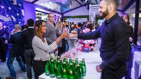 Woman receiving a drink from waitstaff at Vogue Fashion's Night Out