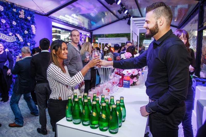 Woman receiving a drink from waitstaff at Vogue Fashion's Night Out