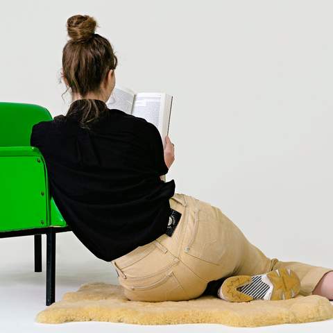 Woman reading book next to green chair