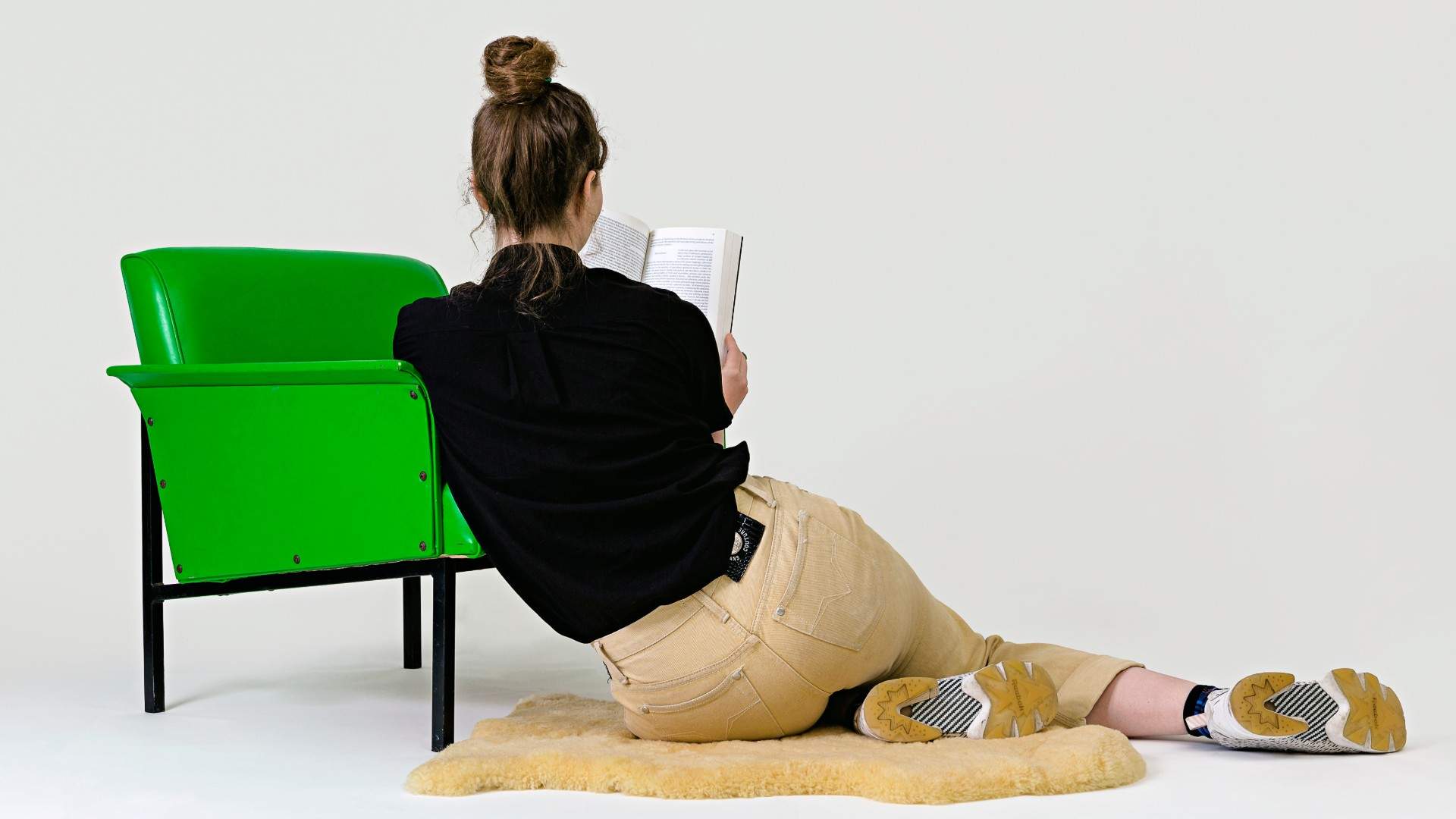 Woman reading book next to green chair