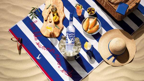Blue and white striped towel with Grey Goose bottle of vodka and snacks