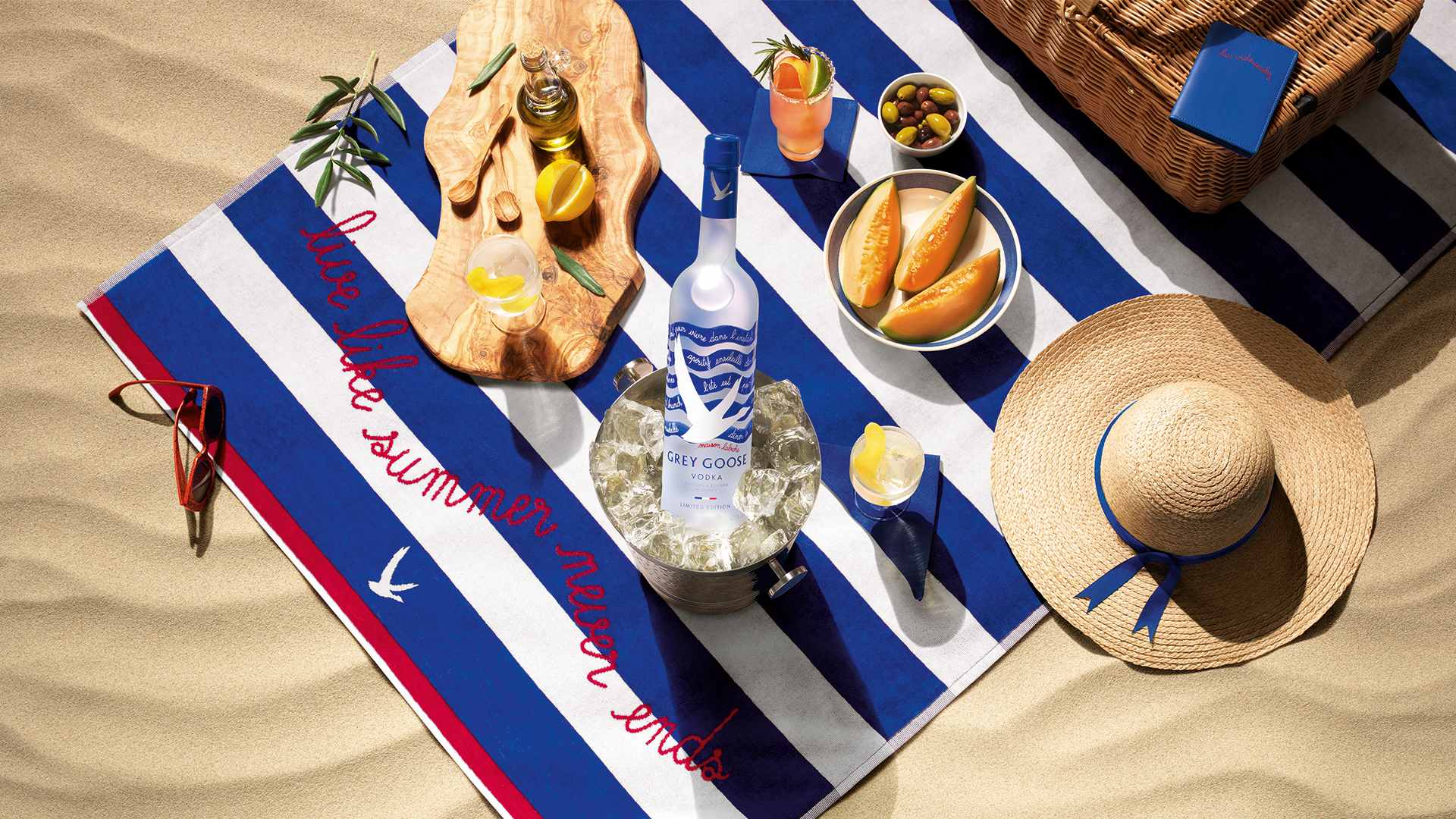 Blue and white striped towel with Grey Goose bottle of vodka and snacks