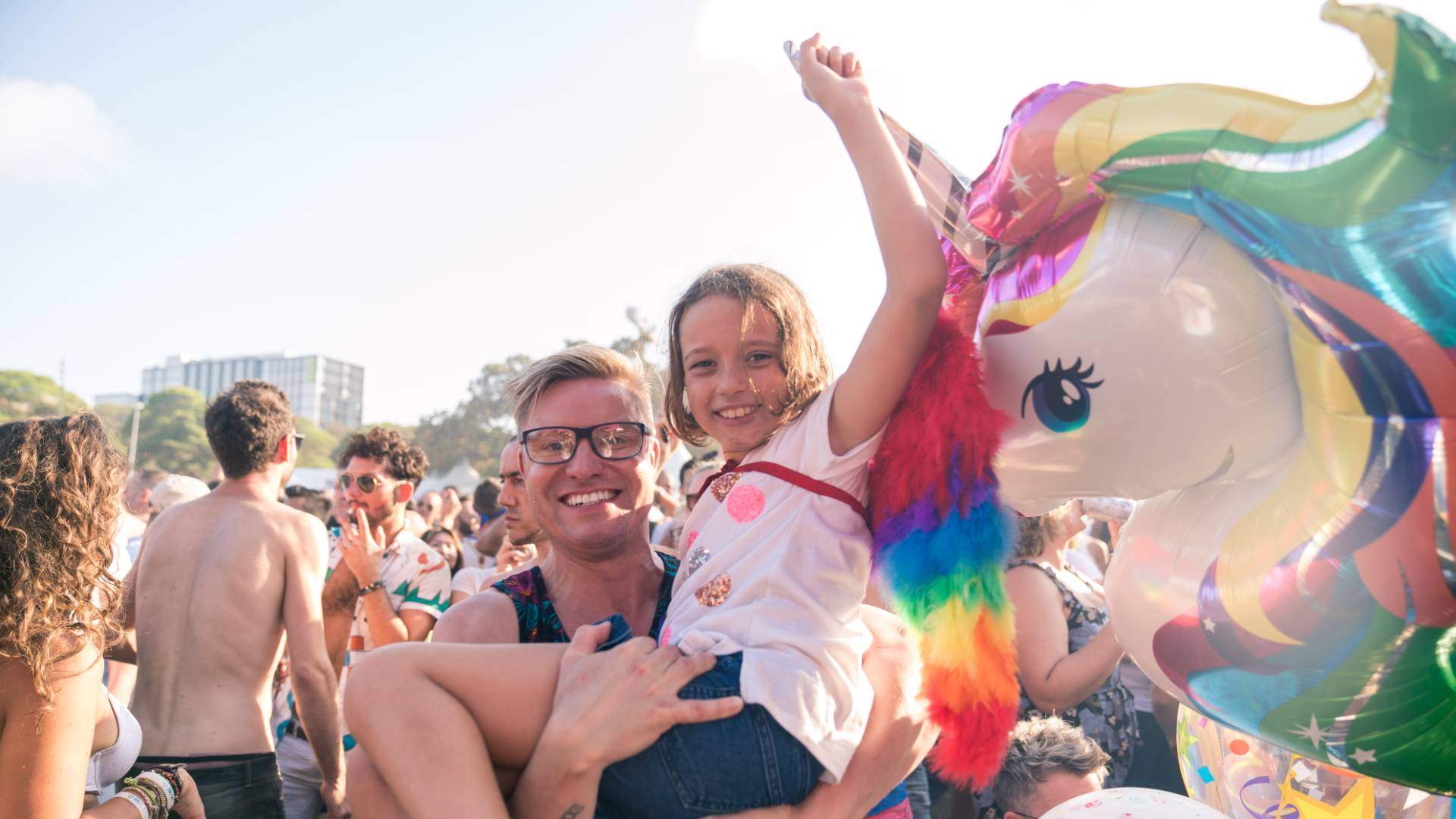Parent holding child holding a unicorn balloon