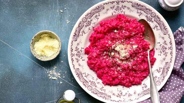 Beetroot risotto with parmesan cheese on a plate on a concrete surface