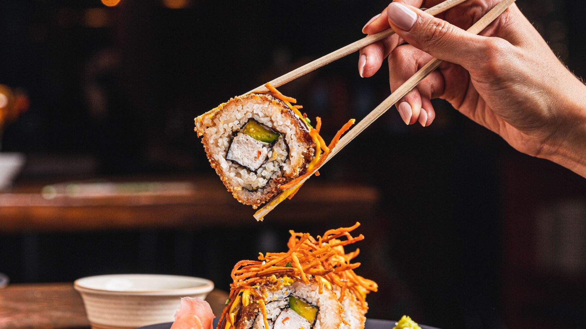 vegan sushi being picked up with chopsticks at Calle Rey - — one of the best vegan restaurants in Sydney