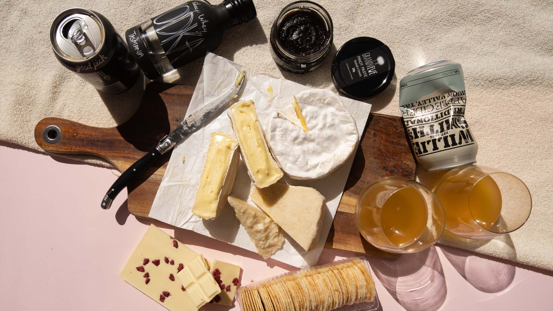 Cheese subscription gift including brie, pinot paste and cider on a wooden board