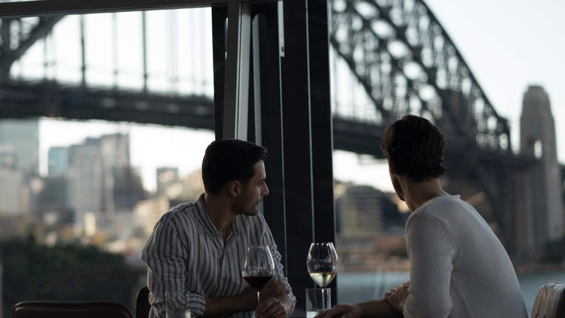 Couple enjoying wine with views across Sydney Harbour towards the Sydney Harbour Bridge from Quay Restaurant, The Rocks