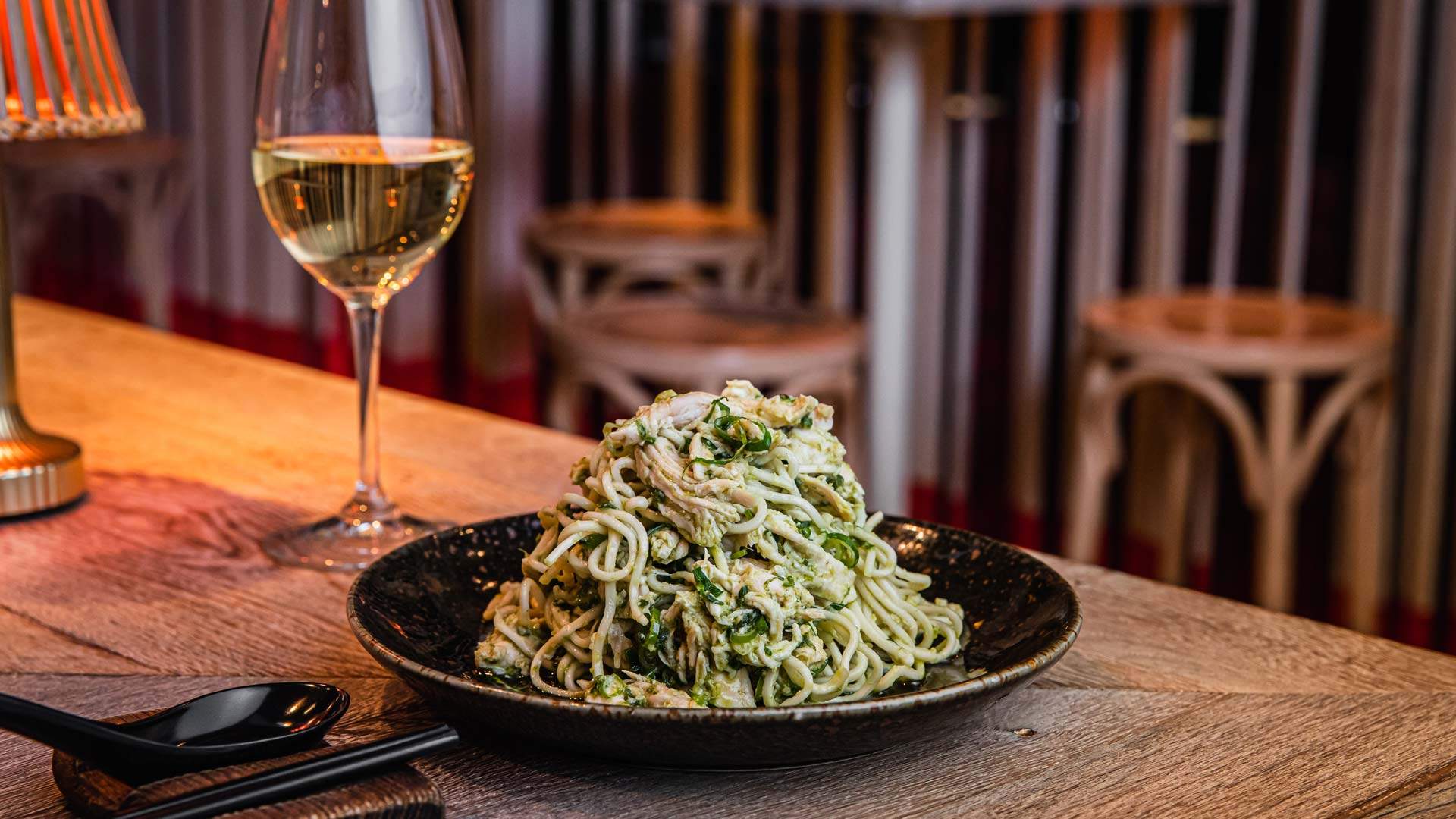 a tower of noodles with a glass of wine on the side at Spice Temple in Sydney