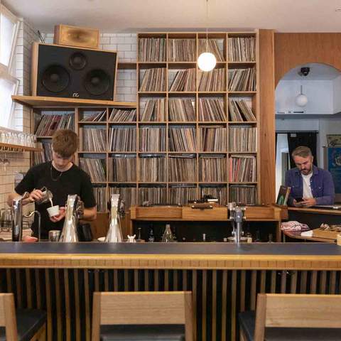 two bartenders working at the bar with a big shelf full of records — Waxflower — one of the best wine bars in Melbourne