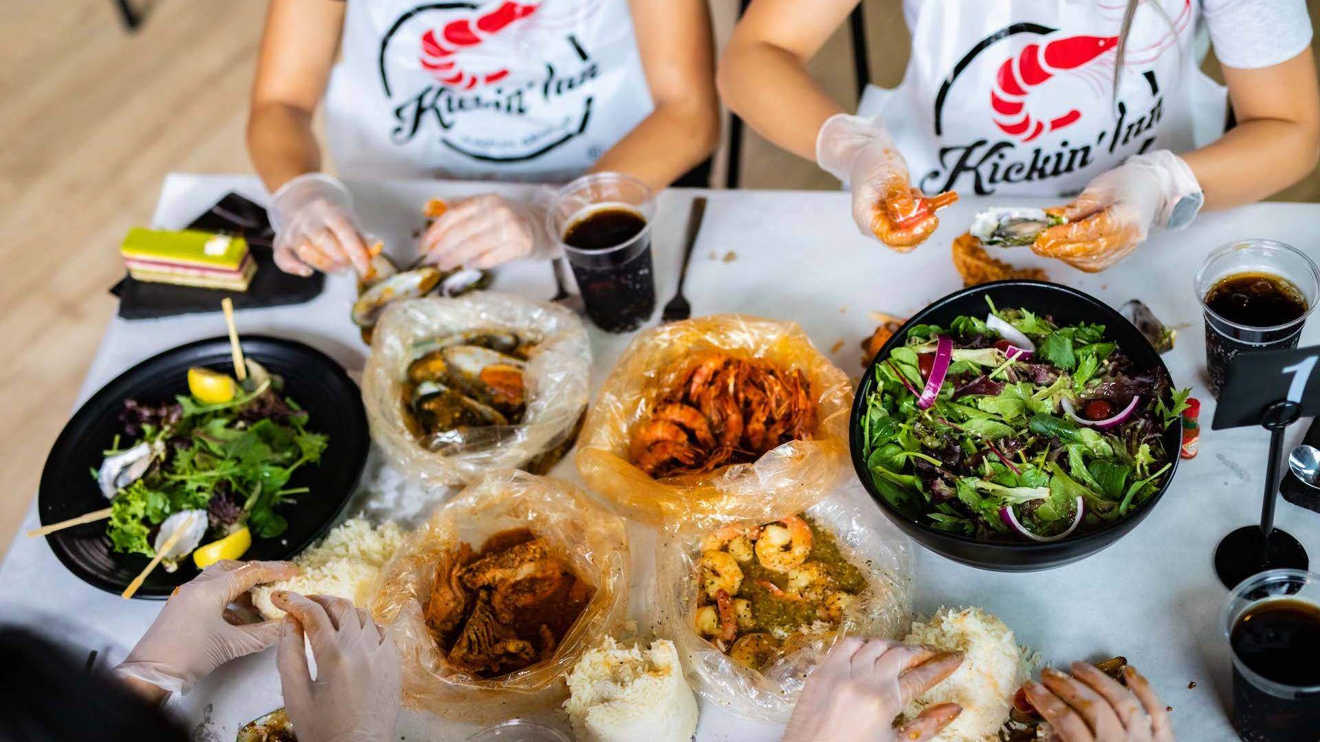 A selection of spicy seafood being eaten by people wearing bibs at Kickin'Inn Melbourne - one of the best seafood restaurants in Melbourne.