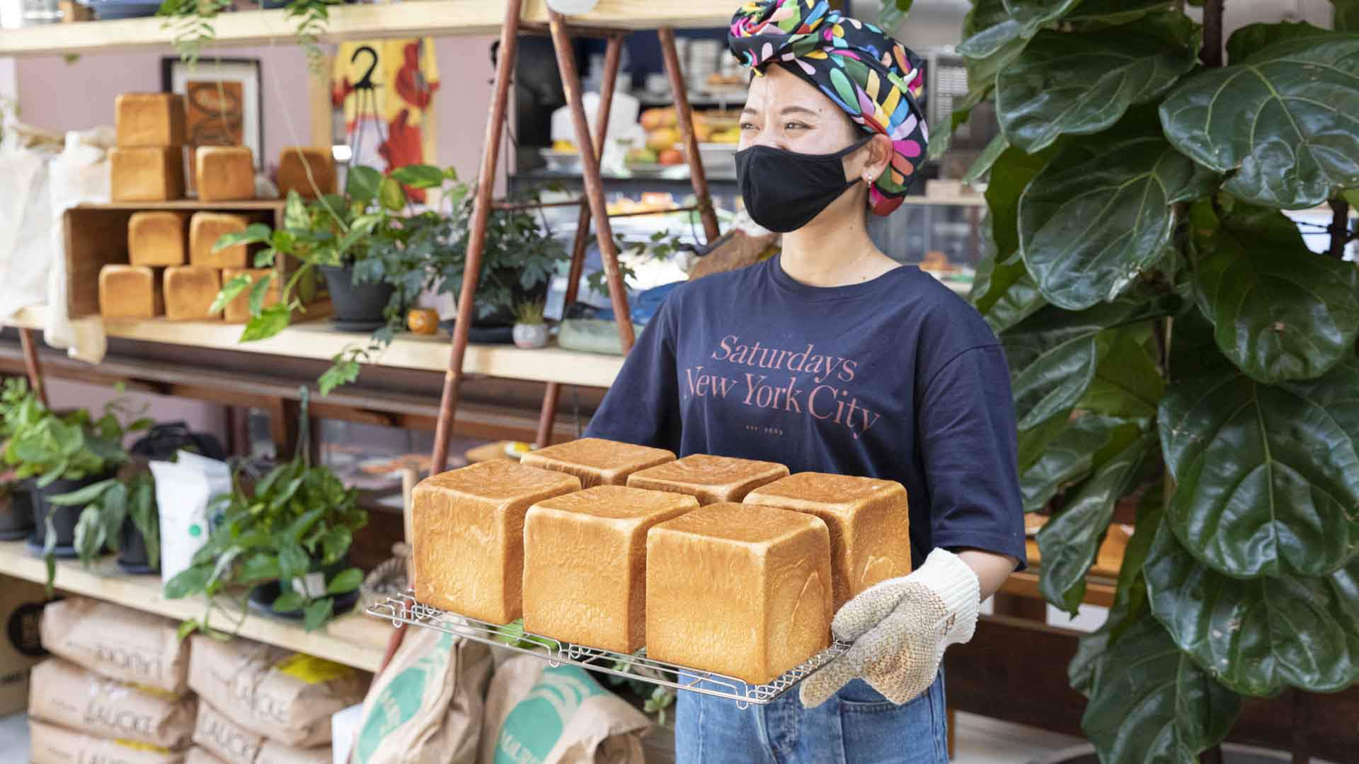 A person holding a tray of freshly made bread loaves. 