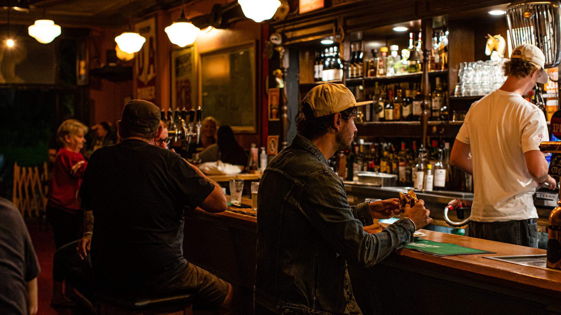 A person is eating a burger at Pub Life Kitchen bar - home to some of the best burgers in Sydney