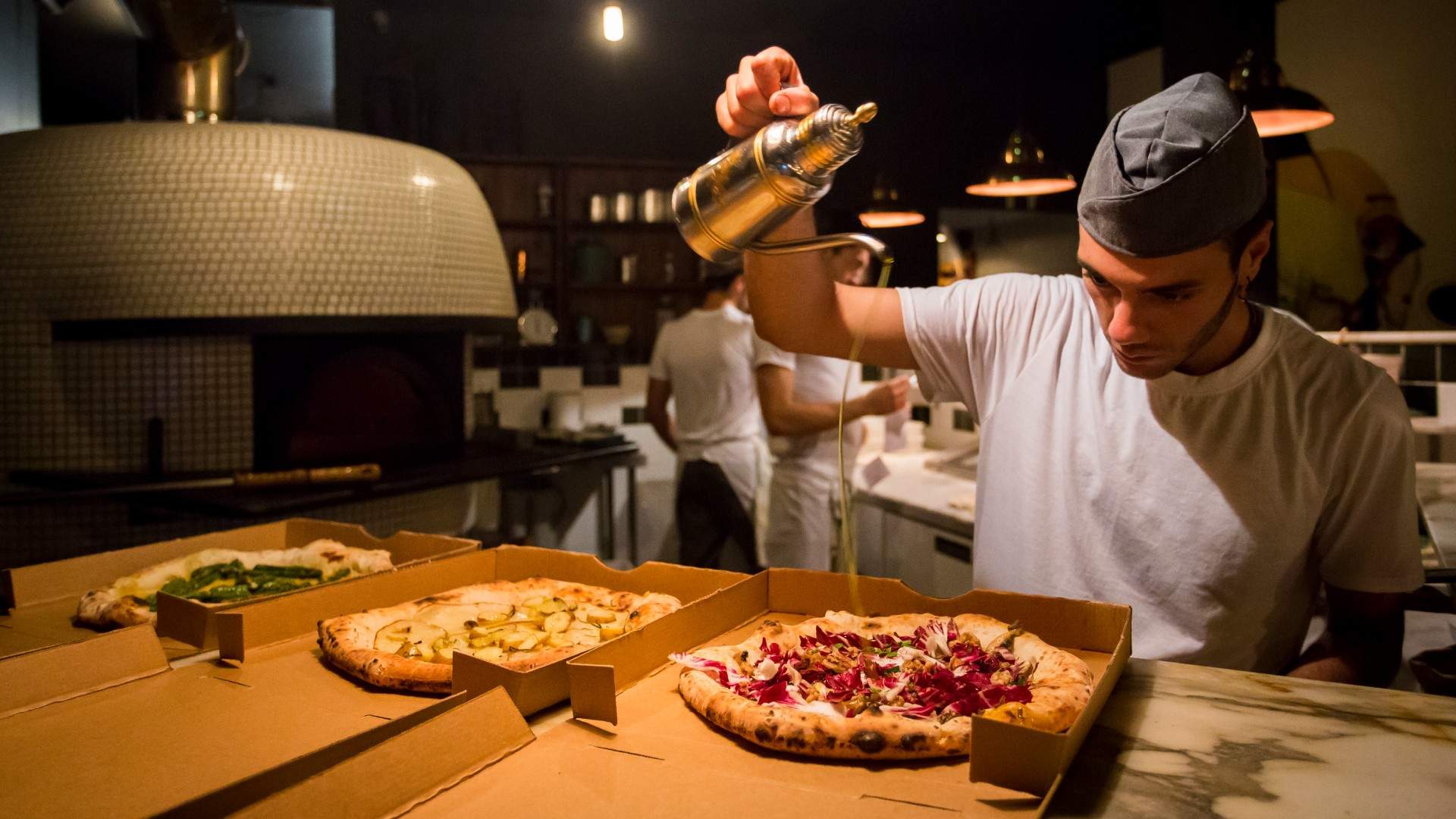 pouring olive oil on takeaway pizza at Gigi's Pizzeria — one of the best vegan restaurants in Sydney