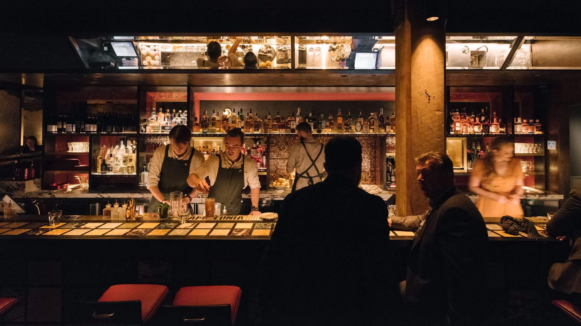 two people drinking at the bar while bartdnders make drinks at Apollonia - one of the best bars in Sydney