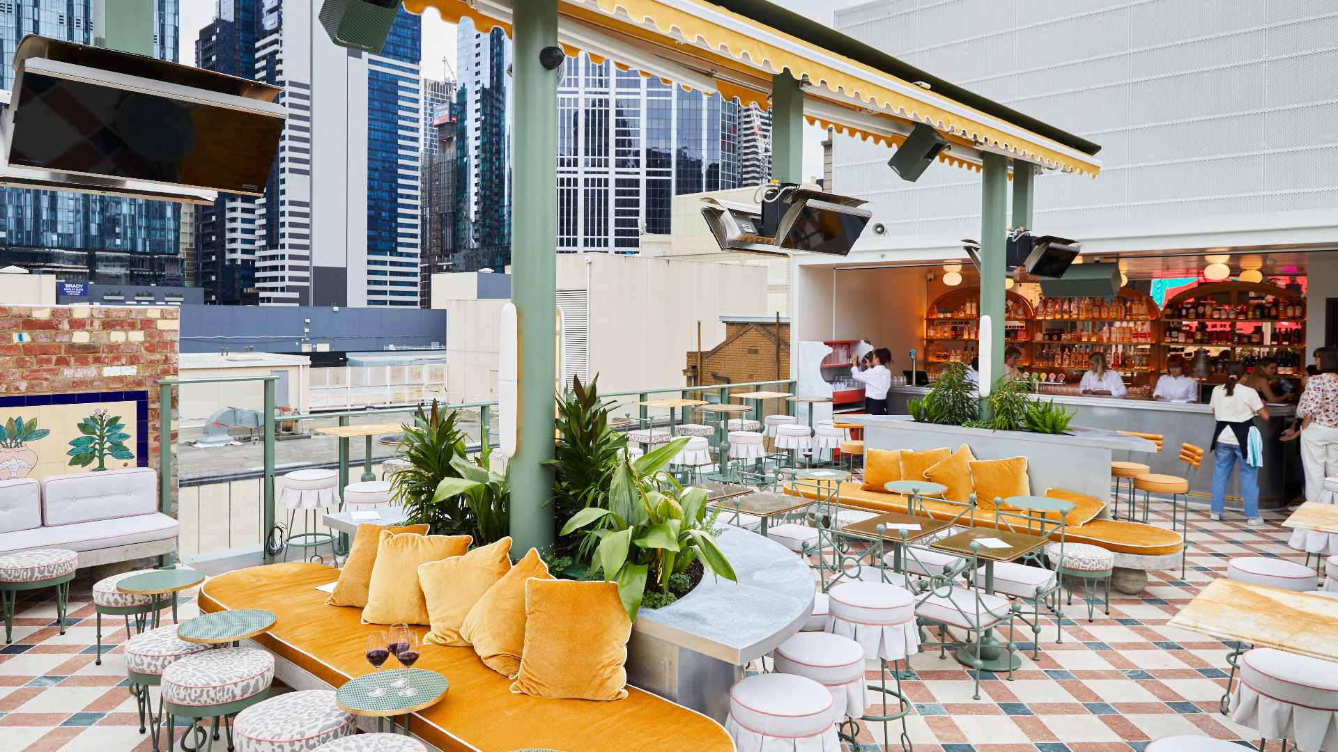 Openair rooftop bar with plants and yellow banquette seating