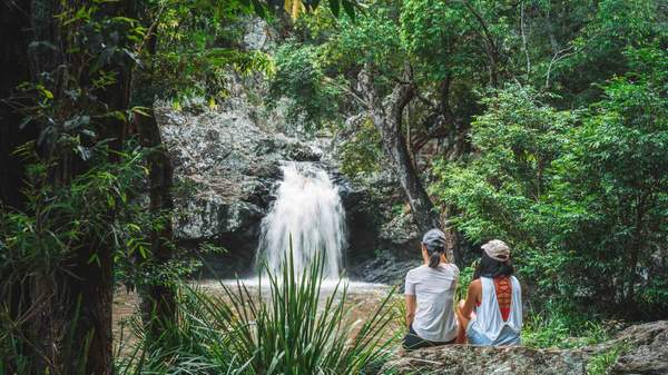 Two people sitting overlooking a waterfall