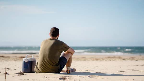 Man sitting on beach looking out to sea