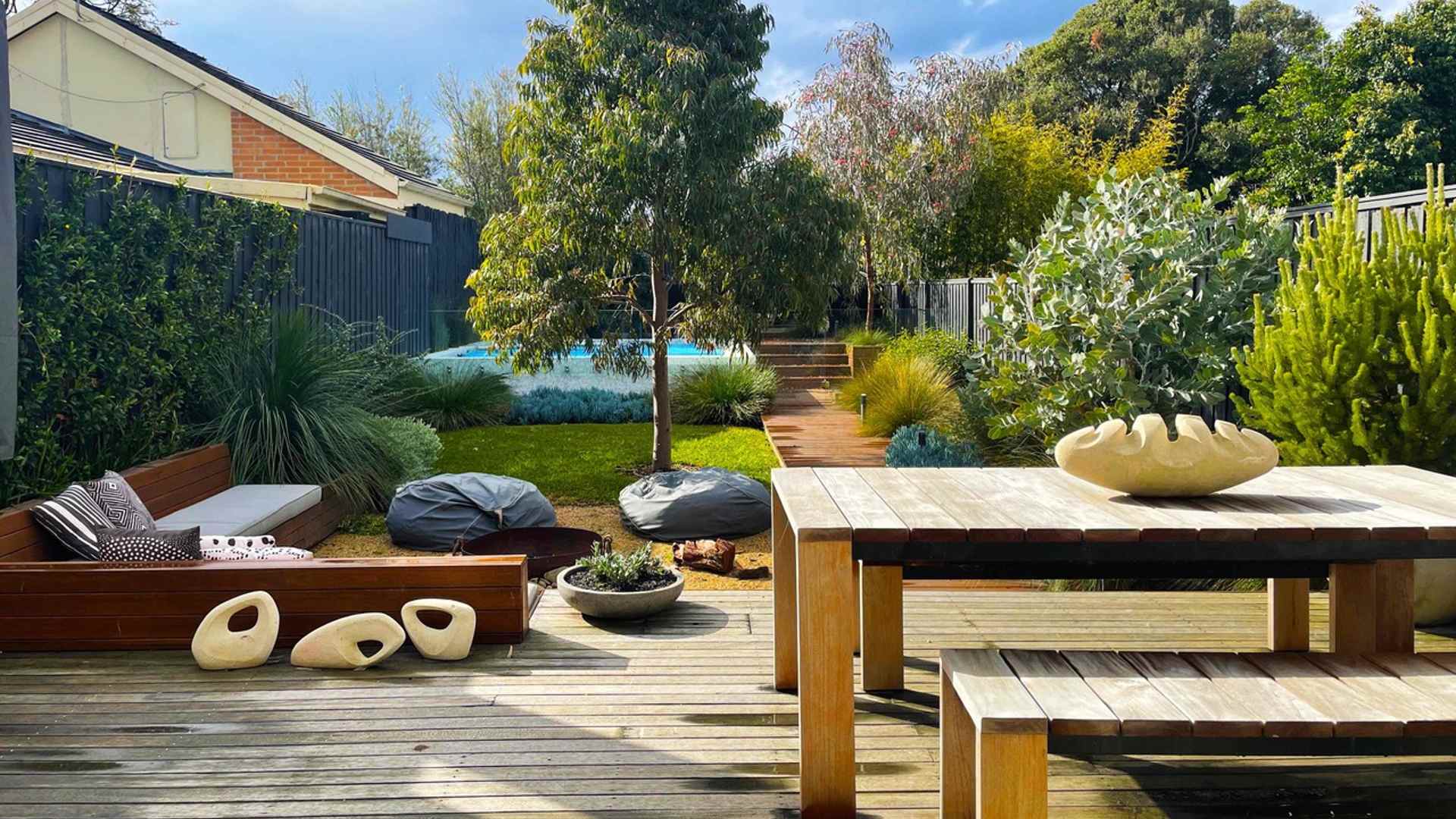 Garden with a deck opening onto green space with trees