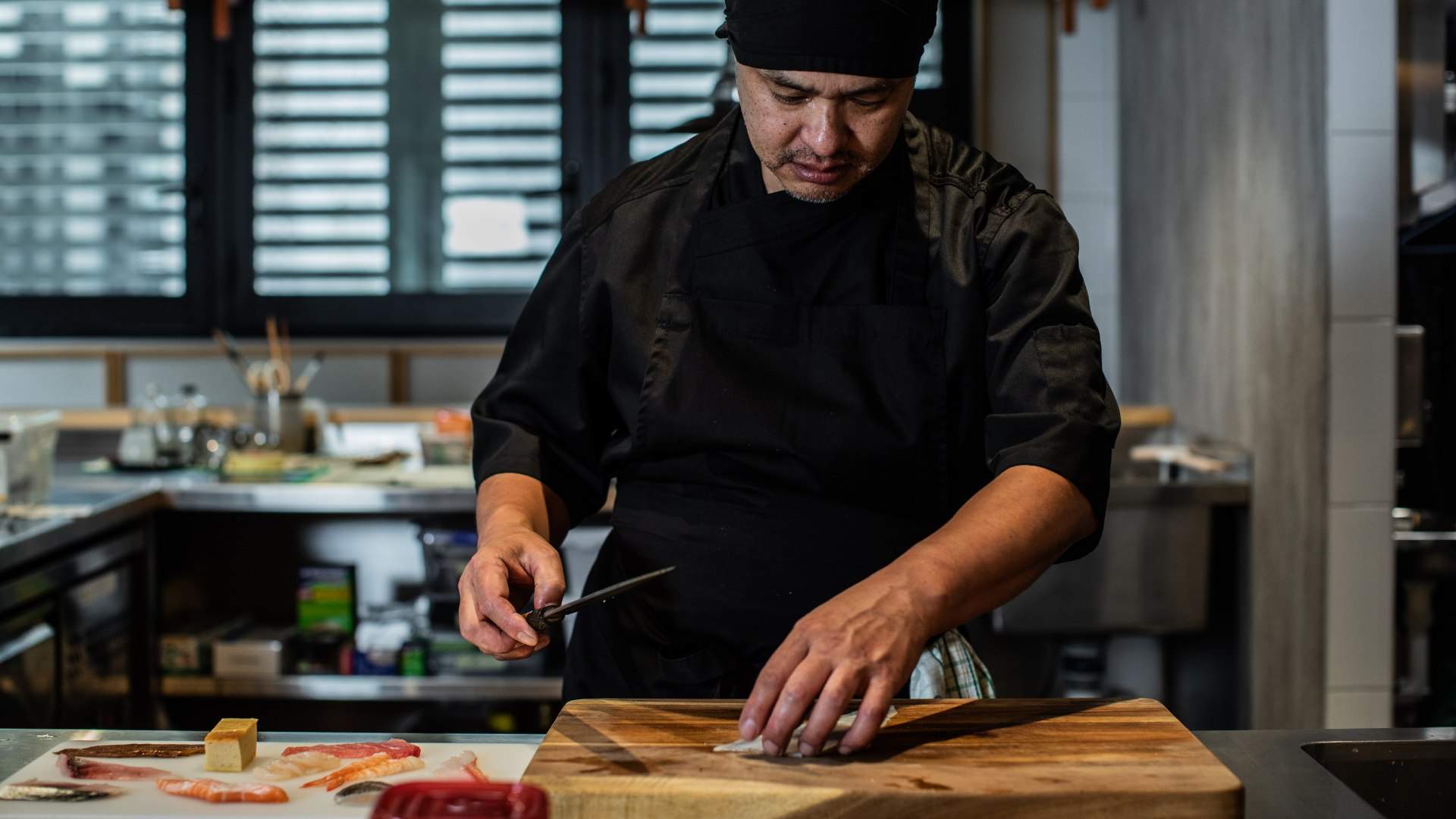 A chef preparing food at Besuto - one of the best seafood restaurants in Sydney - omakase