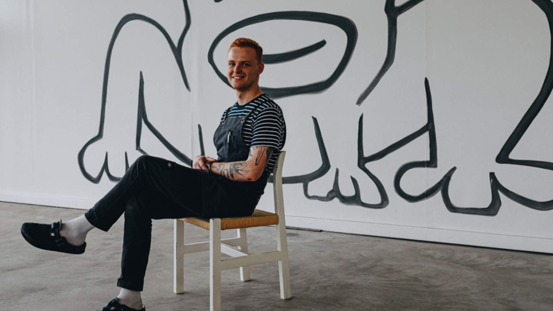 Chef George Wintle sitting in a chair with black-and-white art of the wall behind him