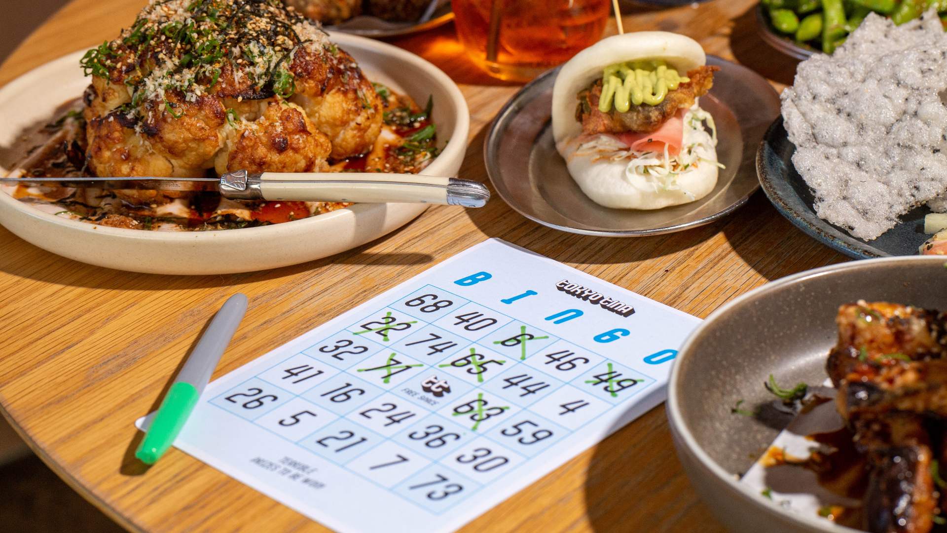 Bingo card on a table full of food and cocktails