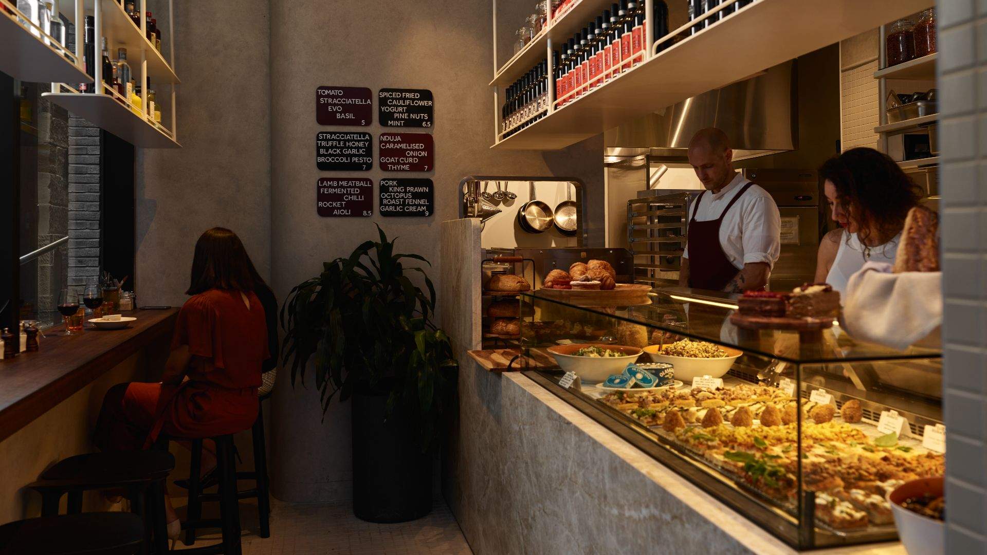 Intimate dine-in scene with food window and workers behind cafe bar at Bar Mammoni