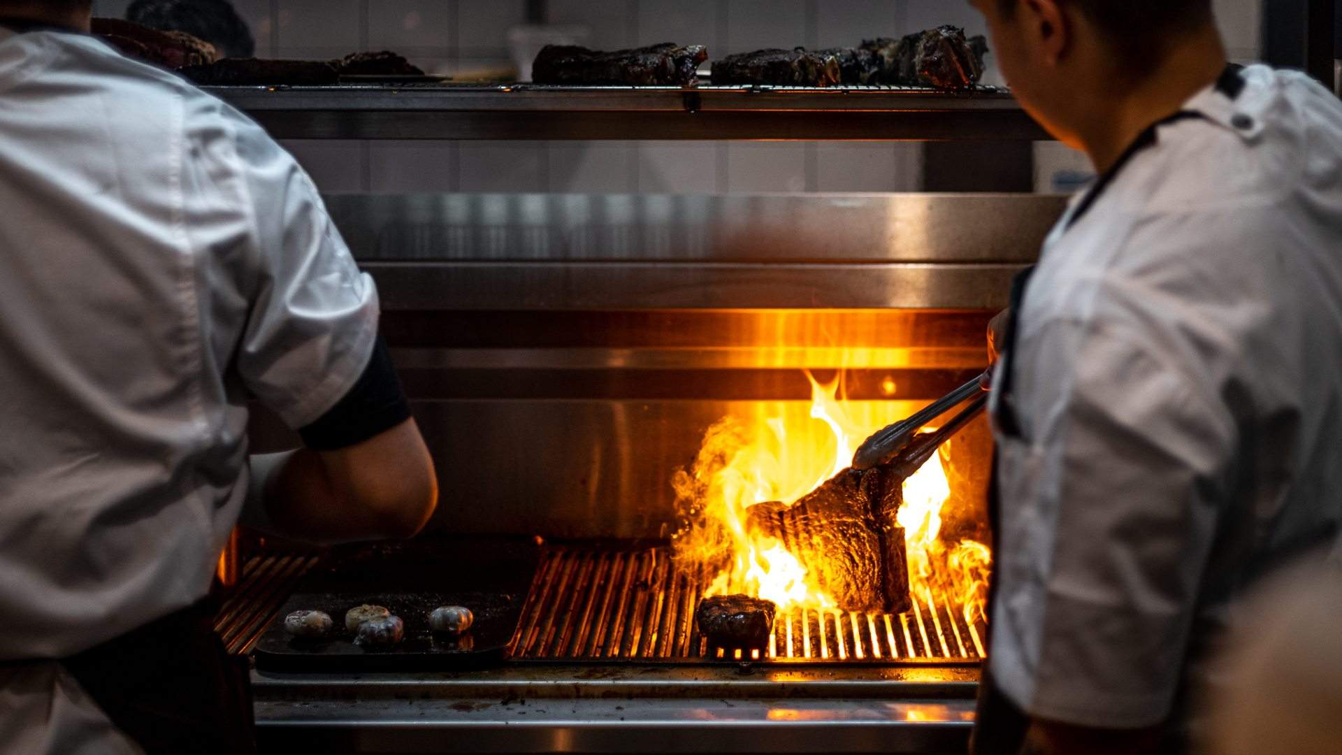 chefs cooking steaks over the fire grill at botswana butchery and grill - home to some of the best steaks in sydney