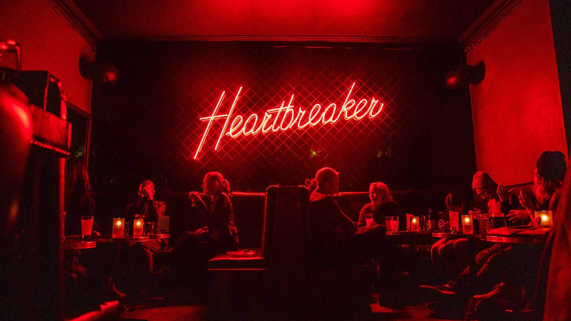 Best bar melbourne - a red neon sign heartbreaker CBD with people drinking beneath