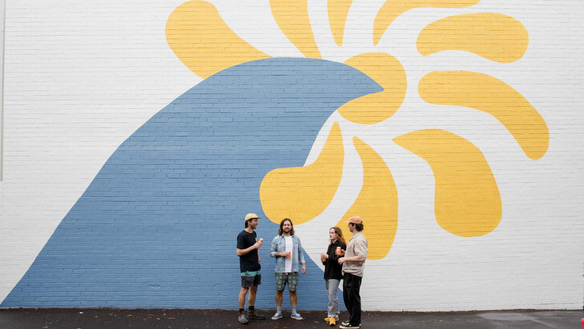 People standing outside a large mural at Freshwater Brewing Co in Sydney. 