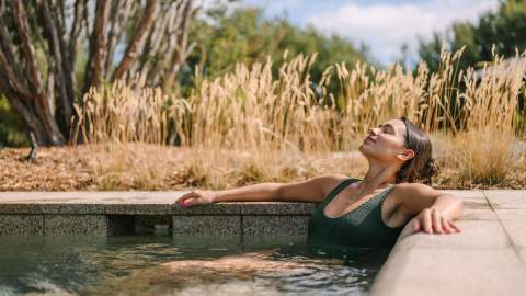 A woman relaxing in a natural hot pool outside at Alba Thermal Pools - one of the best spas in Melbourne