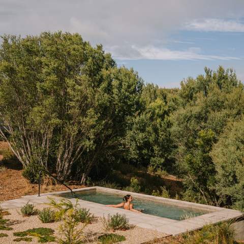 A person swimming in a large natural hot pool outside at Alba Thermal Pools - one of the best spas in Melbourne