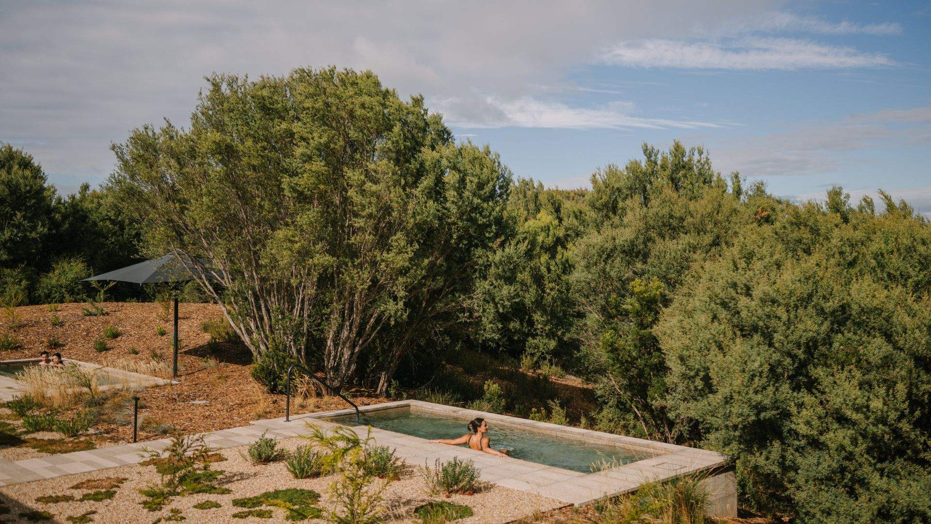 A person swimming in a large natural hot pool outside at Alba Thermal Pools - one of the best spas in Melbourne