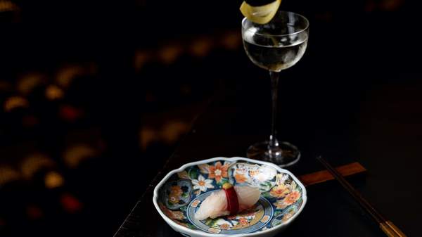 A glass of wine next to a plate which presents a small portion of a Japanese dish served at Kisumé, Melbourne.