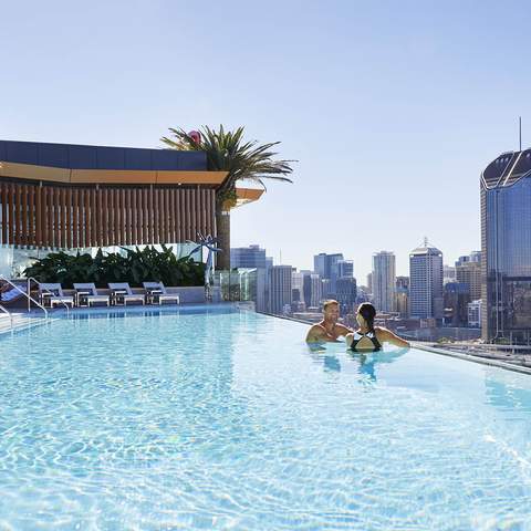 People swimming in the pool overlooking the city at Emporium South Bank