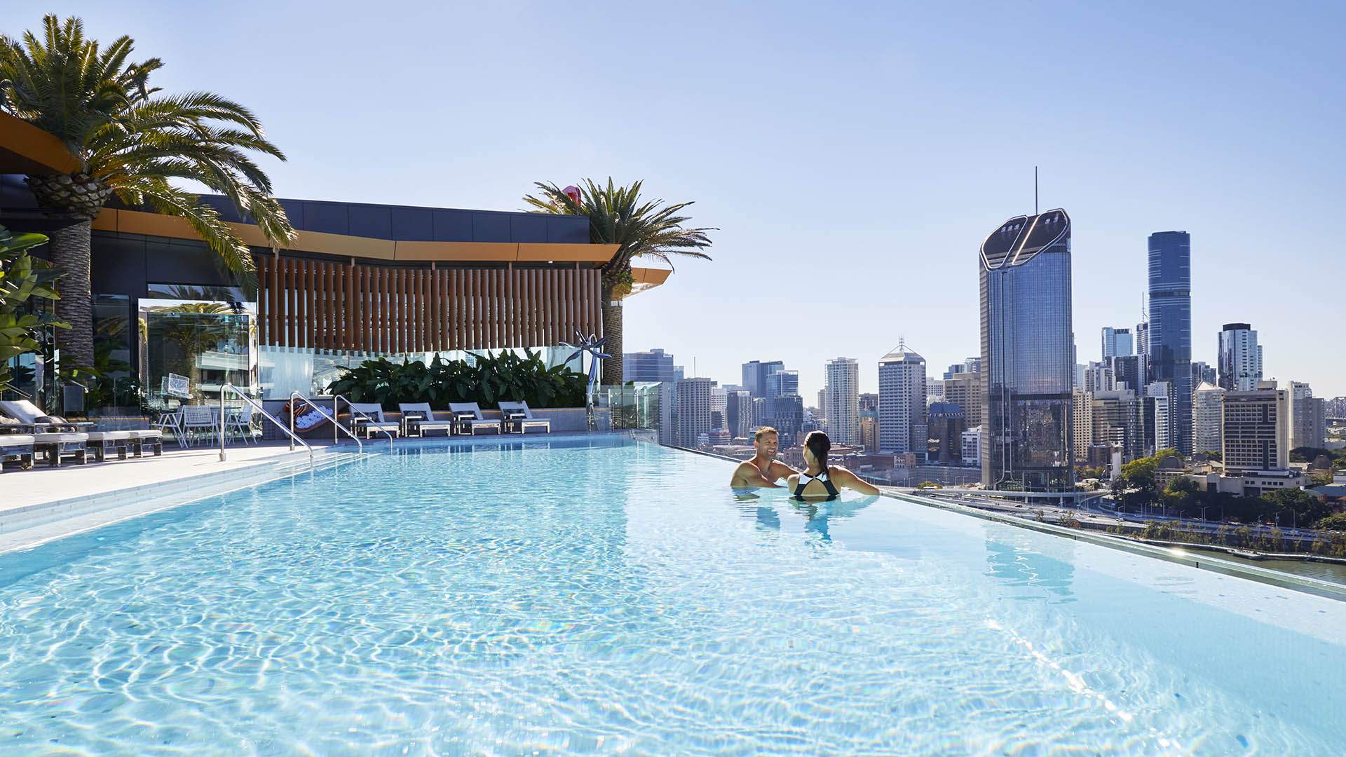 People swimming in the pool overlooking the city at Emporium South Bank