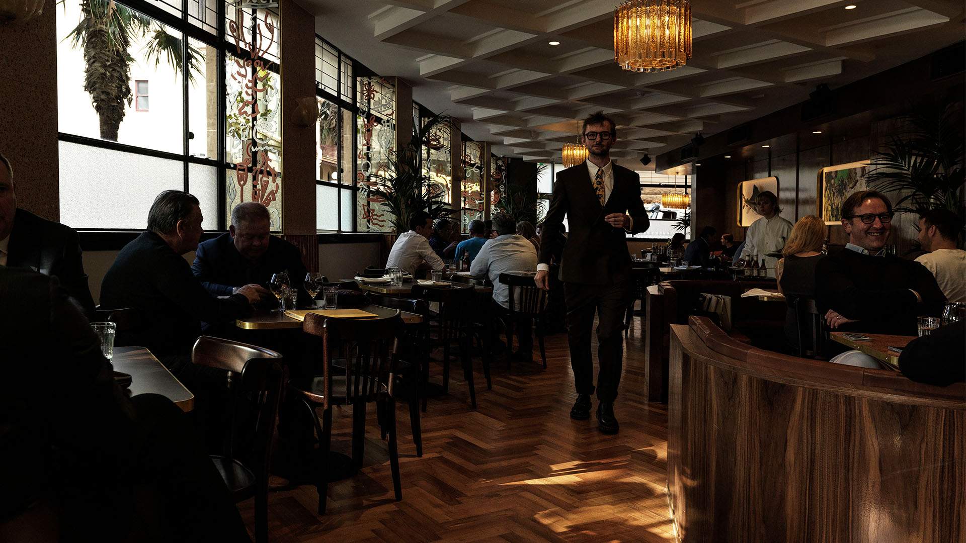 a witer walking in the main dining room by the bar at Clam Bar - home to one of the best steaks in Sydney